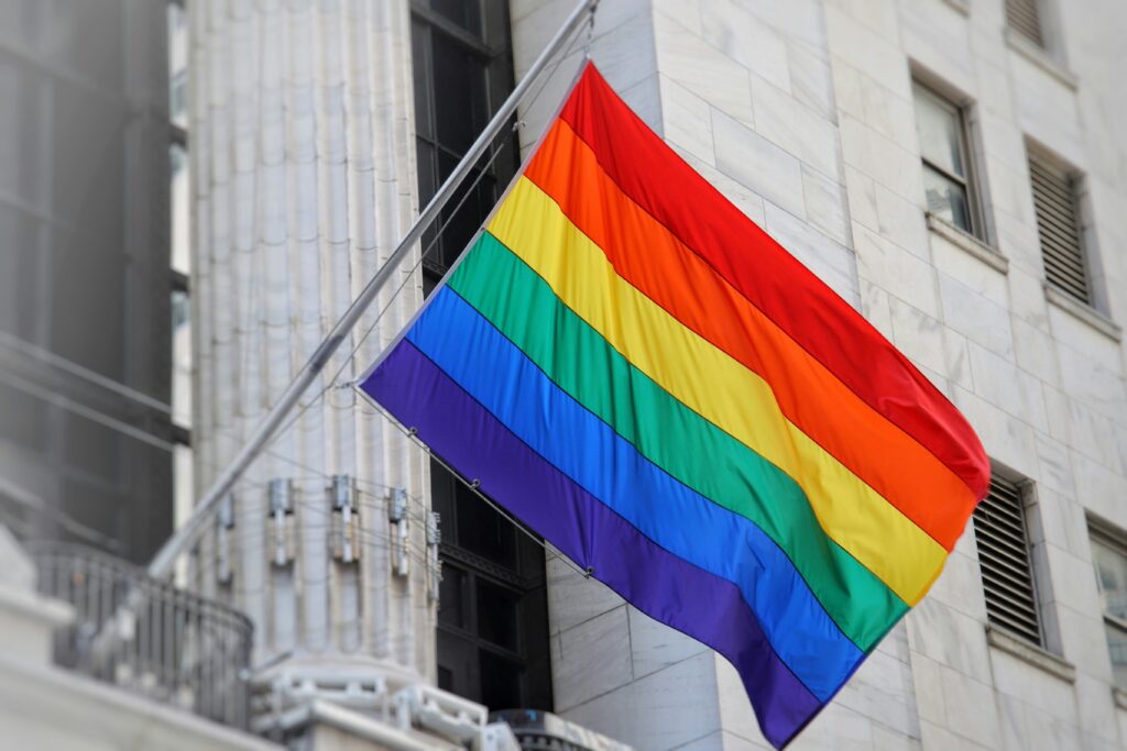 Rainbow pride flag waving on building.